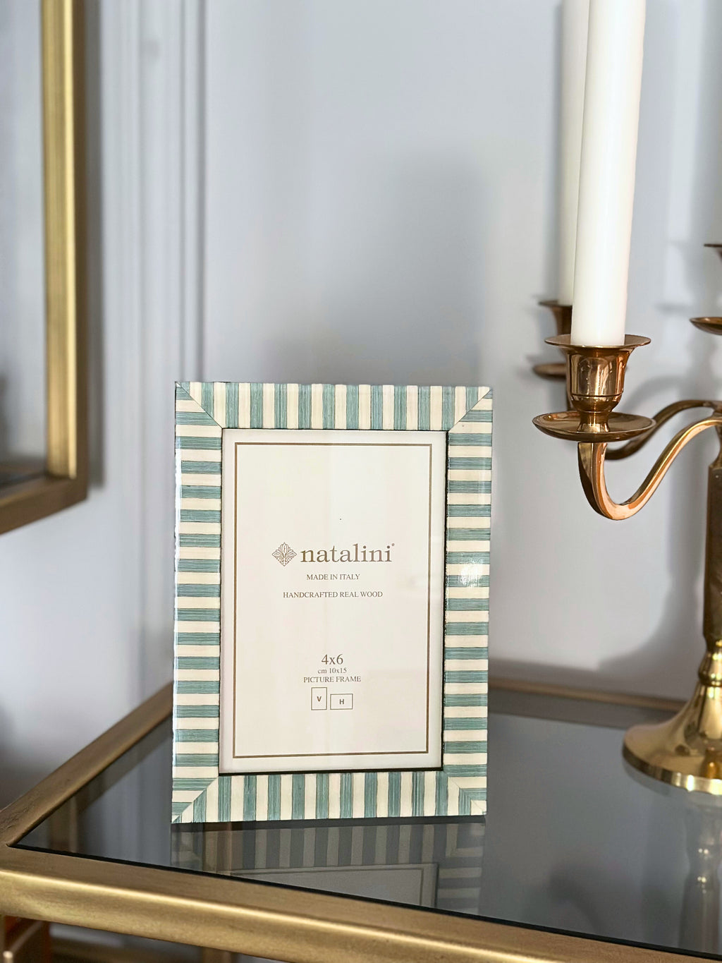 Striped photo frame with 'natalini' branding on desktop